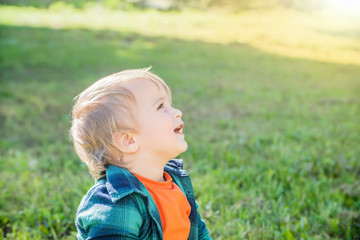 little blond boy on a green grass background on a Sunny day