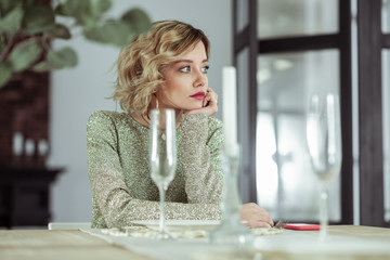 Wife waiting for husband sitting at the table with empty glasses