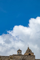 Summer blue sky and church roof with religious cross, view of ancient town of Matera, the Sassi di Matera, Basilicata, Southern Italy, cloudy summer August day