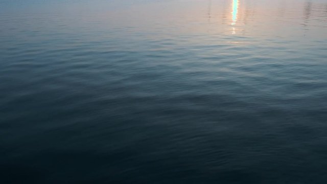 Marine picture. Blue sea water with a reflection of the sky on its surface of white volumetric clouds. Calm excitement on the sea surface on the sunset. Texture sea water with small waves. Copy space