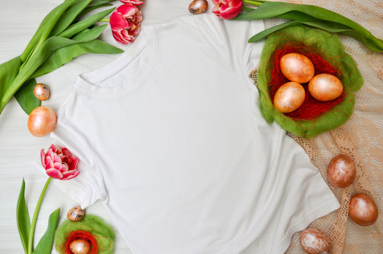 White T-shirt template with flowers tulips and Easter eggs in a green nest. quail and chicken painted eggs. Easter theme. Mock up white t-shirt of plowed and spring theme, isolated under the text.
