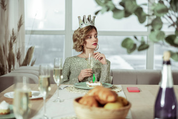 Curly woman with short hair cut drinking champagne on her own