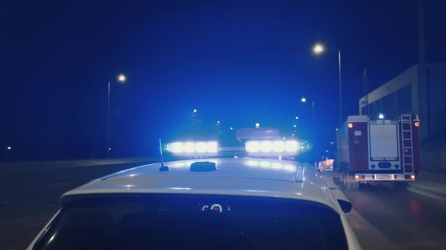 An accident on the highway in a major resort town. A team of ambulance paramedics and a fire truck rescue people. 911. Bright lights, flashing lights and sirens of a police patrol car. Car Crash