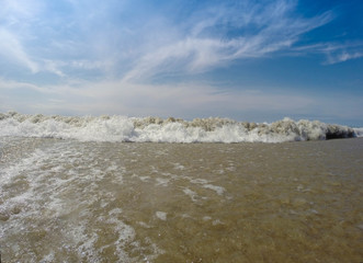 Close up view of a wave coming into shore with a vibrant blue sky