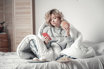 Woman eating burger and waiting for message from her boyfriend