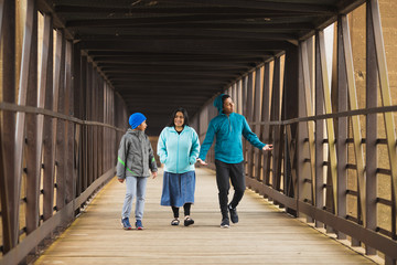 Fototapeta premium Hispanic Mother Walks With Sons On A Bridge