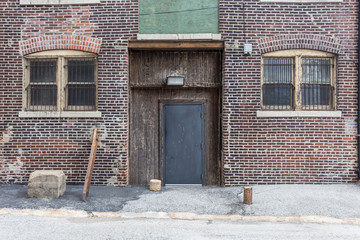Fototapeta na wymiar Brown brick warehouse building with barred windows and metal door