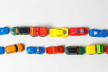 Mehrfarbige Spielzeugautos aus Kunststoff sind auf weißem Hintergrund aufgereiht. Stereotype Ausrichtung der Subjekte ist ein Zeichen von Autismus. Selektiver Fokus. Kopieren Sie Platz für Text. Staus Luftverschmutzung Konzept.