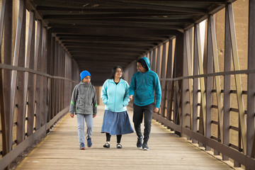 Fototapeta premium Hispanic Mother Walks With Sons On A Bridge