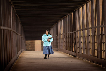 Fototapeta premium Hispanic Woman Walking Down A Bridge With Her Bible