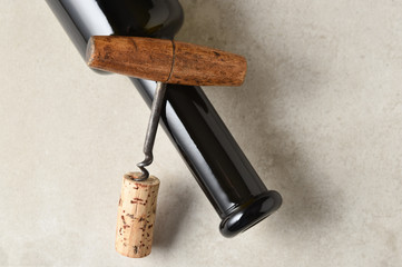 Wine bottle laying on its side with a corkscrew and cork