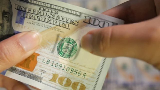 A 100-dollar US bill being inspected closely to verify its authenticity