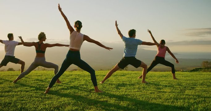 Yoga class at sunset, happy diverse group of young people practicing yoga poses together, stretching health and wellness