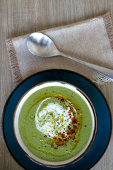 Creamy vegetable soup with kale, cabbage, celery and millet, decorated with olive oil, yoghurt sauce and chilli flakes. Top view.