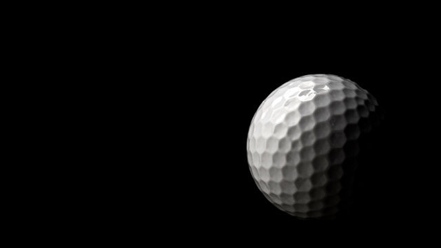 High contrast studio shot of golf ball isolated on black background with dramatic light and copy space