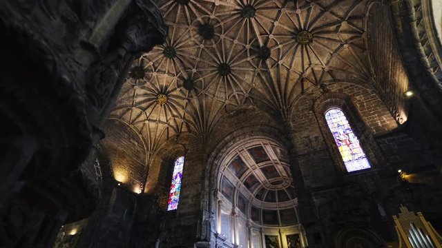 From below dark Interior of majestick cathedral. Panoram on fan vaulted dome and decorated carved ceiling. Portugal, Lisboaz
