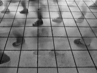 Motion blur image of people walking on metro platform. The image is taken with long exposure so that people's feet look frozen yet also in motion. 