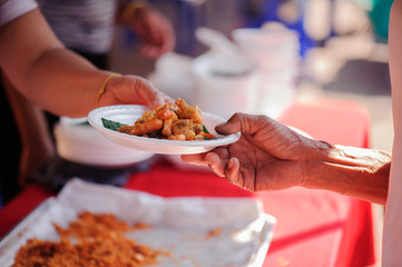 The hands of the rich are giving food to the poor and hungry.