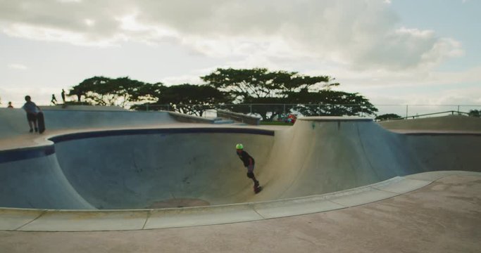 Young skateboarder grinding the coping in a pool bowl, extreme shredder skateboarder kid in skatepark, slow motion