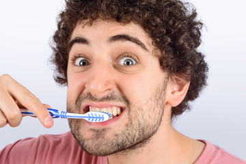 Young funny man washing his teeth.