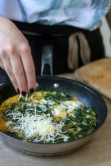 Unrecognizable person making frittata with chicory and cheese. Selective focus.