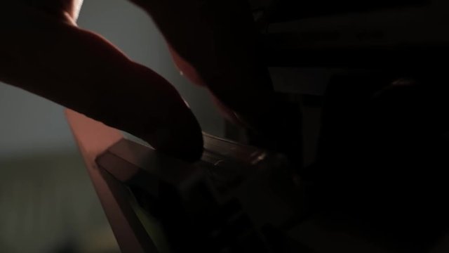 Side close up detail shot, man dj turn the page of cassette in old vintage analogue tape recorder or hifi stereo, dark low light contrast scene, 4H UHD