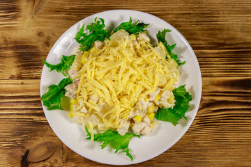 Festive salad with chicken breast, sweet corn, canned pineapple, cheese and mayonnaise on wooden table
