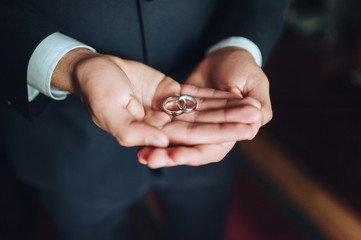 Close up of two wedding rings on  groom's palms. 