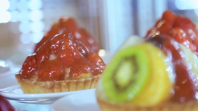 Extreme close up view of fresh juicy fruity tarts and different desserts on display in restaurant fridge. Sweet tooth, delicious, no diet. Healthy food, food tourism