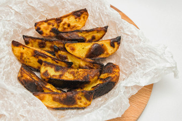 A spoiled dish, overcooked burnt potatoes on a wooden board. A bad kitchen
