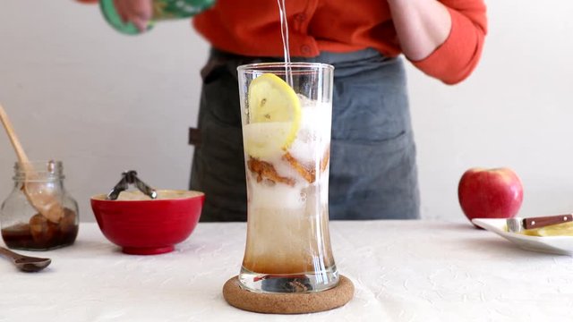 Pouring sparkling water into glass cup with apple cinnamon preserved in sugar
