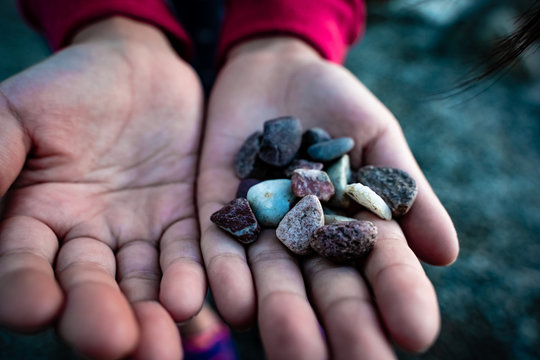 Child&rsquo;s young hands holding colorful pebbles