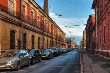 Naklejka na ściany i meble Old grunge street in Russian town with parked cars
