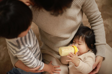Obraz na płótnie Canvas 赤ちゃんにミルクを与える親子