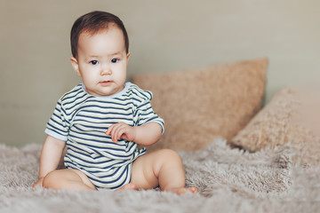 serious Baby girl sitting at bed at home. White vintage childroom. Childhood concept. looking at camera