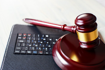 Wooden judge gavel on keyboard laptop computer. Concept of online auction, legal system, law and technology.