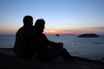 Loving couple are admiring the sunset,  Saint-Malo, Brittany, France