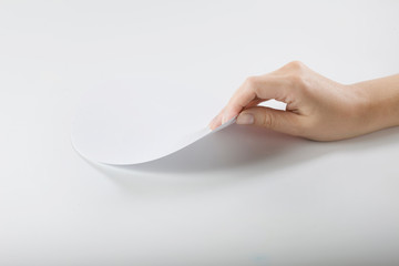 arm bends a sheet of paper. looks under the sheet. flips a page.