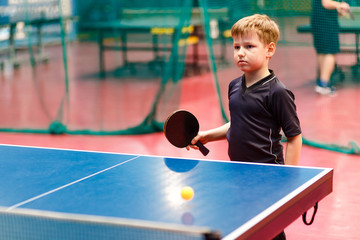 Caucasian boy playing table tennis at the blue table