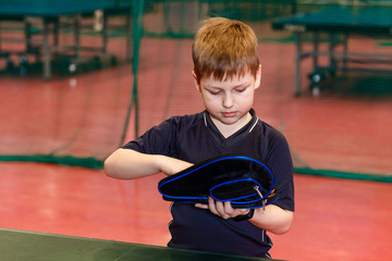 the boy is holding a cover for a racket for table tennis