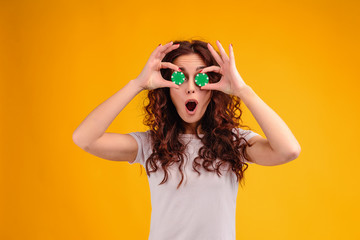 Attractive brunette girl with curly hair isolated over yellow background with poker chips in her hands. Online casino concept