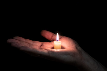 paraffin candle memory lit on the palm of a man, the background is dark