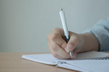Female hand with pen writing on notebook.