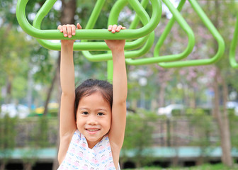 Close up little girl playing on gymnastic ring on playground outdoor.