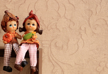 Art sculpture of boy and girl in love sitting together with legs crossed on a edge of wooden platform