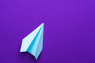 white paper airplane on a purple background