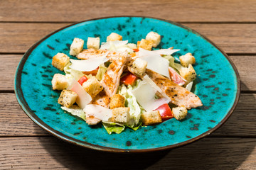 Fresh caesar salad in white plate on wooden table