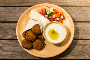 falafel with salad and sauce on a wooden table