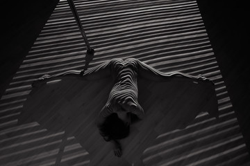 A beautiful woman dancing at the pole in the light of the projector. Young sexy slim woman doing splits