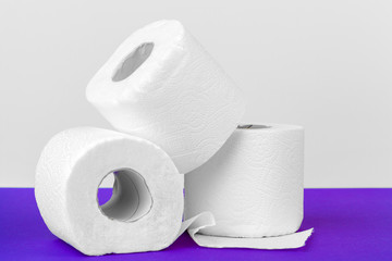 Toilet paper rolls isolated on white table with purple background